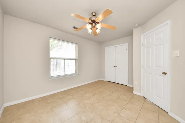 an empty room with windows and fan
