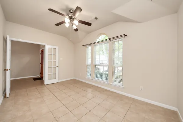 an empty room with windows and chandelier fan