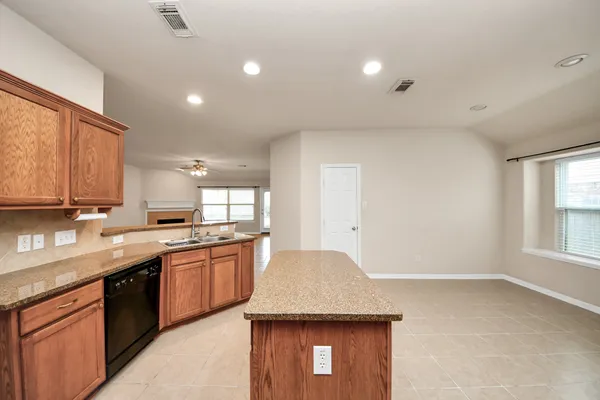 a kitchen with stainless steel appliances granite countertop a stove top oven a sink dishwasher a refrigerator and a dining table with wooden cabinet