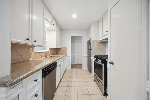 a large kitchen with granite countertop a stove top oven a sink a counter space and cabinets