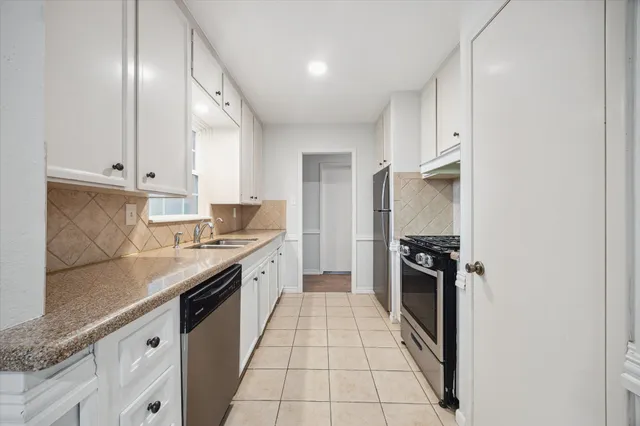 a large kitchen with granite countertop a stove top oven a sink a counter space and cabinets