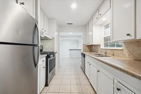 a large kitchen with a large counter top a sink a refrigerator and cabinets