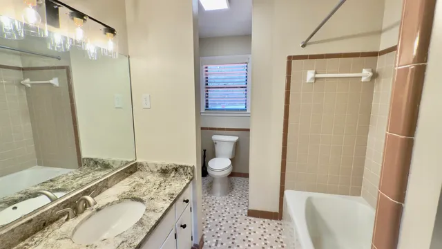 a bathroom with a granite countertop sink toilet and shower