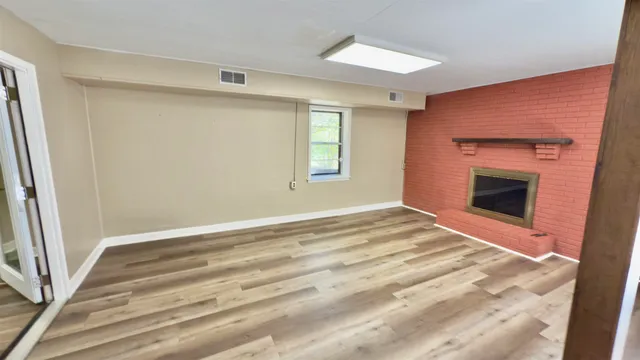 a view of empty room with wooden floor and fireplace