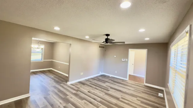 a view of an empty room and window and wooden floor
