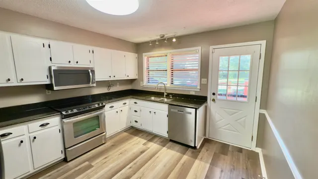 a kitchen with granite countertop white cabinets and white appliances