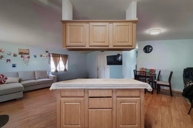 a kitchen with stainless steel appliances granite countertop a refrigerator a sink dishwasher a stove and white countertops with wooden floor