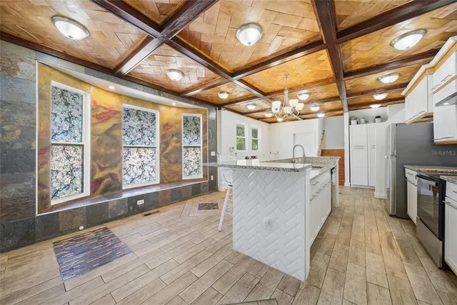 a large kitchen with kitchen island granite countertop wooden floors and wide window