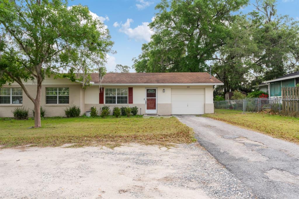 a view of a house with a yard and large tree
