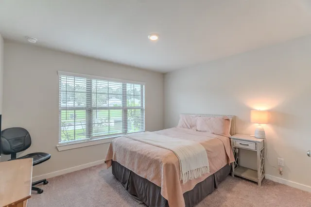 a bedroom with a bed a chair and next to a window