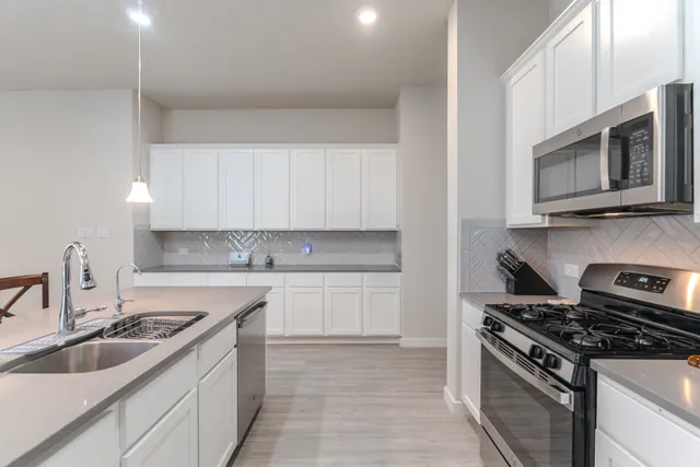 a kitchen with granite countertop a sink stove and microwave