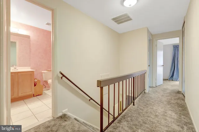 a view of a hallway with bathroom and wooden floor