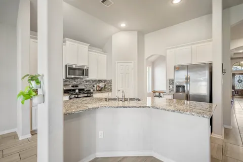 a kitchen with stainless steel appliances granite countertop a refrigerator a sink a stove a counter space and cabinets