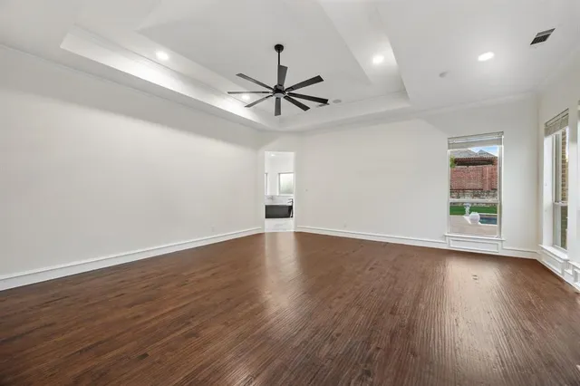 a view of empty room with wooden floor and fan