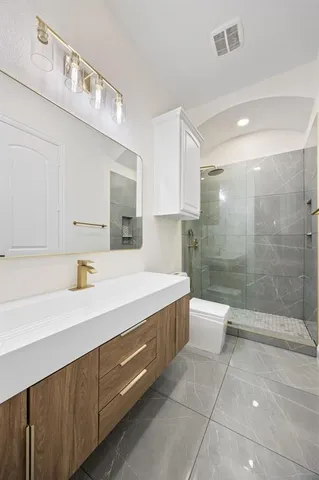 a bathroom with a granite countertop sink a toilet and shower