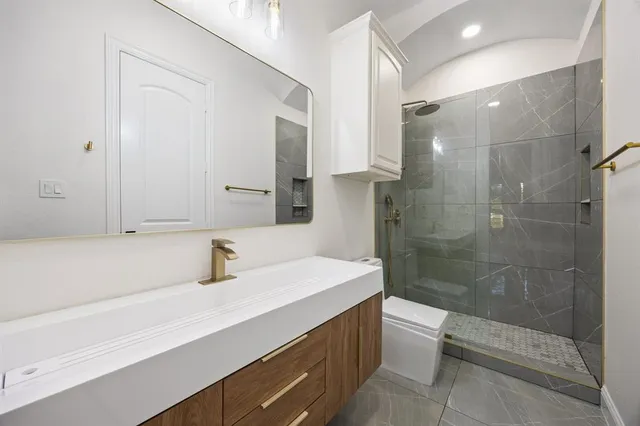 a bathroom with a sink a toilet and shower