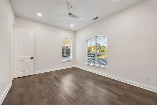 an empty room with wooden floor and windows