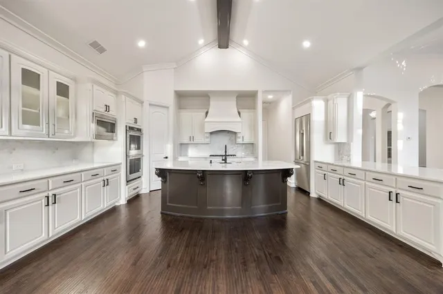 a large white kitchen with stainless steel appliances granite countertop a stove a sink dishwasher and a oven with white cabinets