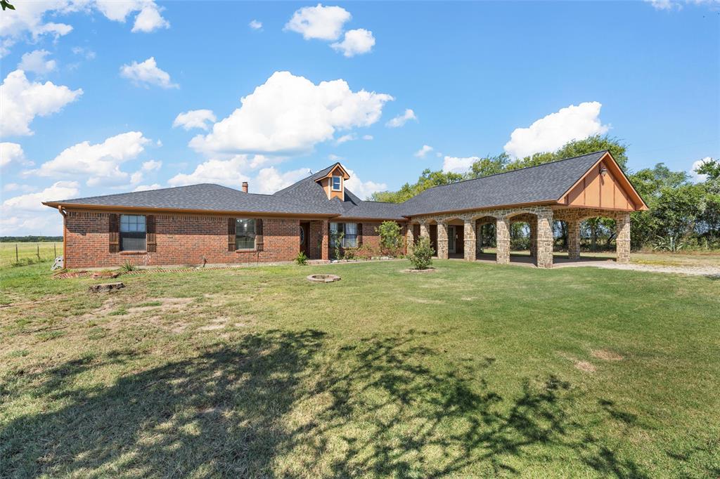 3433 West Tours Road West, TX 76691 - Photo 5 of 40 View of front of house with a front lawn, brick siding, an outdoor fire pit, and roof with shingles
