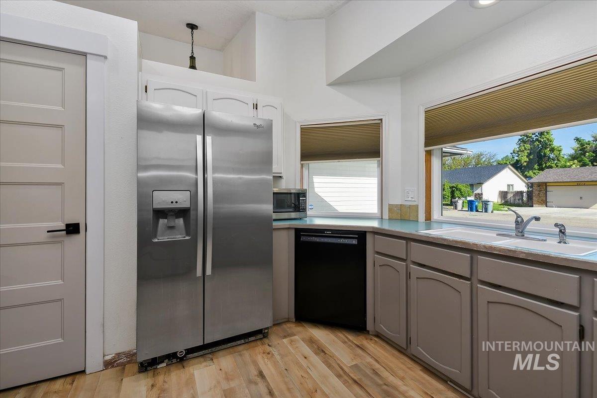9215 West Preece Street Boise, ID 83704 - Photo 6 of 22 Kitchen featuring wood-finish flooring, stainless steel side-by-side refrigerator, light gray base cabinetry, light blue countertops, and a double basin sink with a chrome faucet
