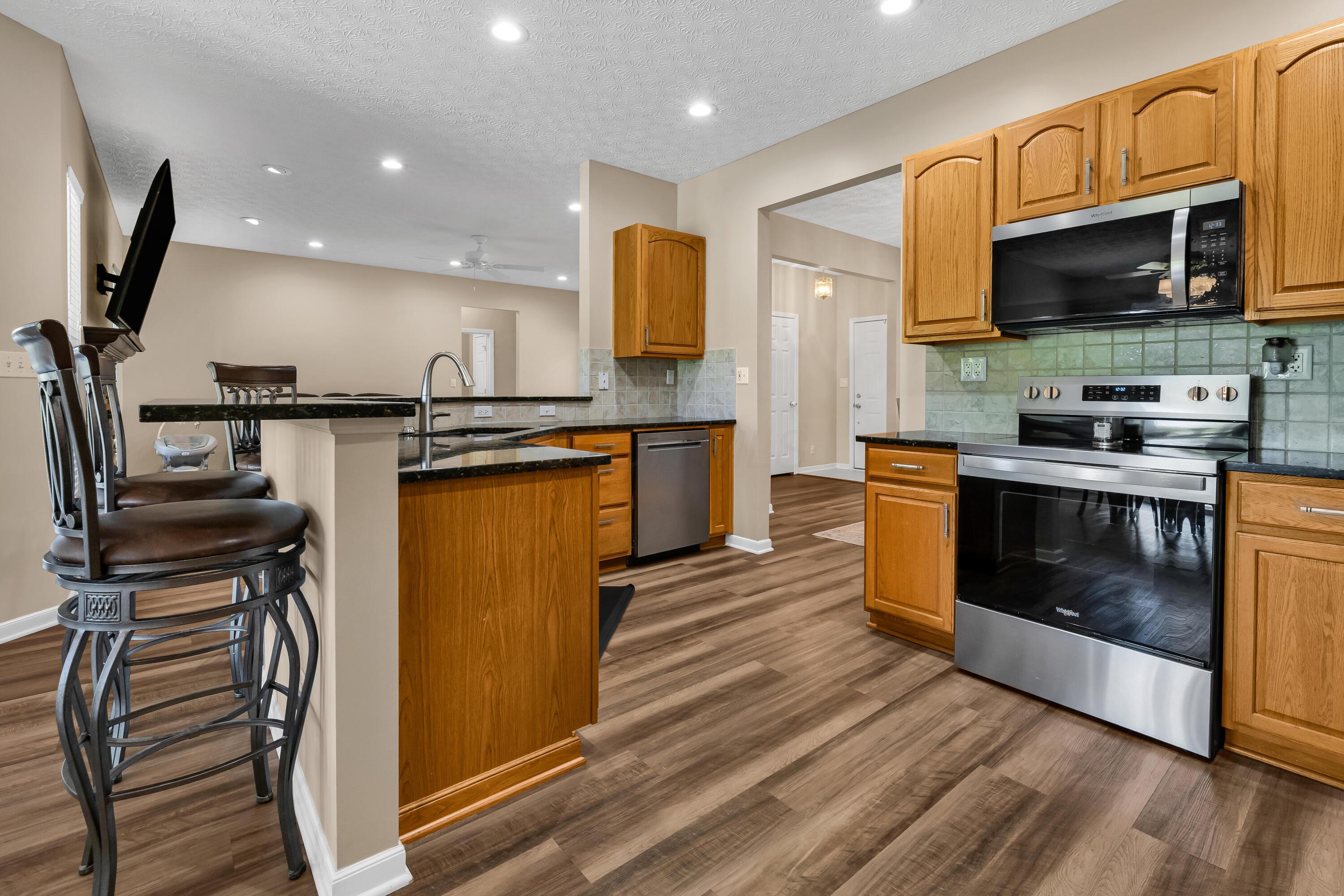 14396 Blamer Road Johnstown, OH 43031 - Photo 14 of 48 • Luxury vinyl plank flooring
• Tan painted walls
• Granite countertops
• New Whirlpool® refrigerator
~ 2025
• New Whirlpool® microwave
~ 2025
• New Whirlpool® electric
range ~ 2025
• New Whirlpool® dishwasher
~ 2025
• Peninsula with breakfast bar
ledge
• Double bowl, stainless steel
sink with sprayer
• New disposal ~ 2026
• Tile backsplash
• Raised panel cabinets