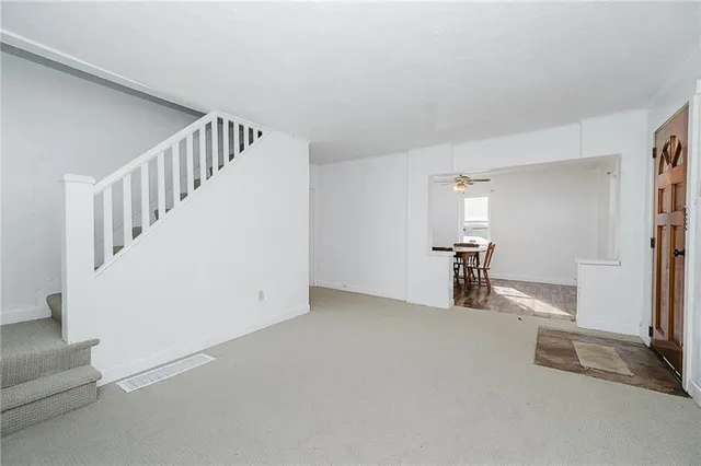 a view of an empty room with stairs and a living room