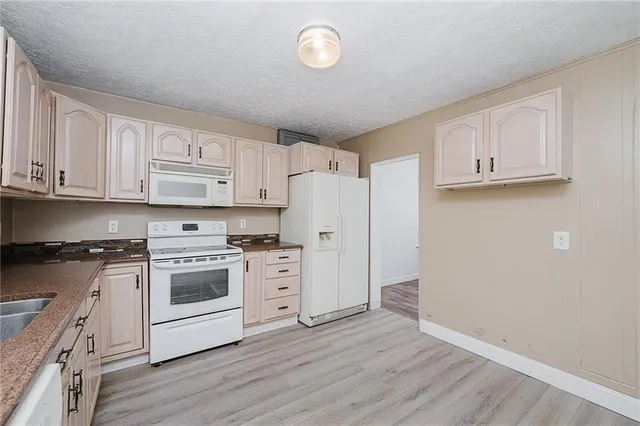 a kitchen with granite countertop white cabinets and white appliances