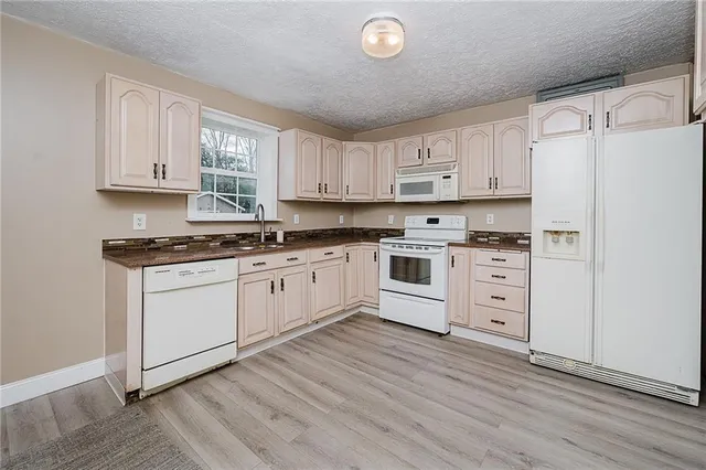 a kitchen with granite countertop a refrigerator and white cabinets