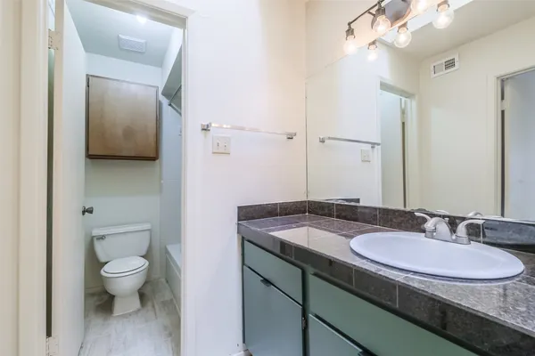 a bathroom with a granite countertop sink a toilet and a mirror