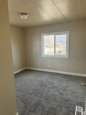 446 Riverside Drive, Unit 24 Wellington, UT 84542 - Photo 10 of 14 Empty room featuring carpet and a textured ceiling