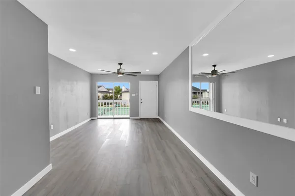 a view of an empty room with wooden floor and a window