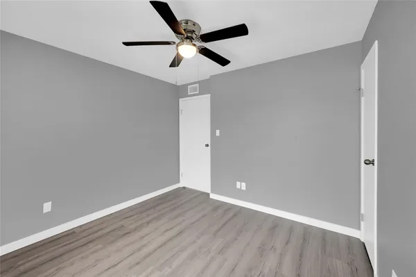 an empty room with wooden floor ceiling fan and window