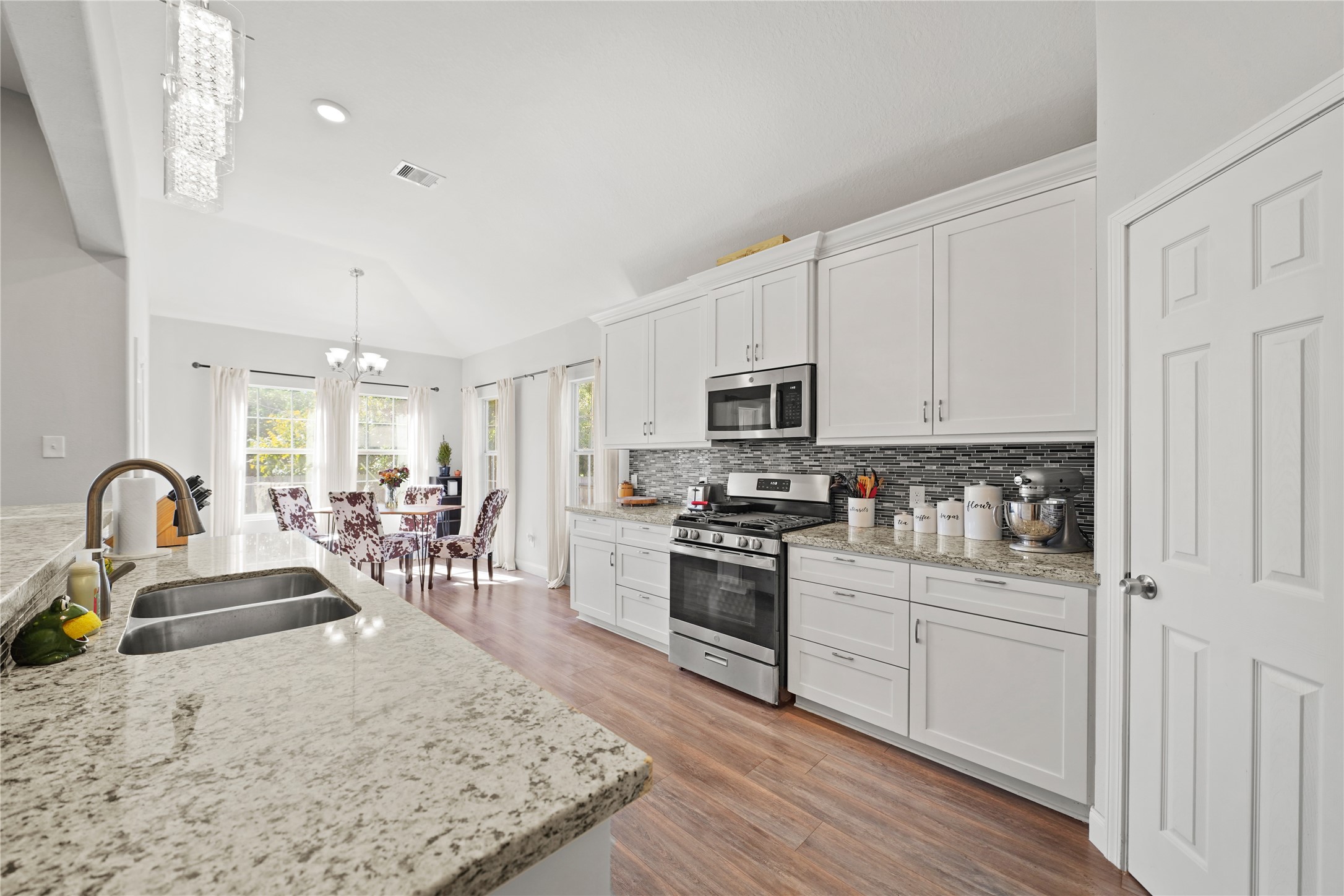 5602 Belmark Street Houston, TX 77033 - Photo 11 of 27 a kitchen with stainless steel appliances granite countertop a stove top oven a sink dishwasher and white cabinets with wooden floor