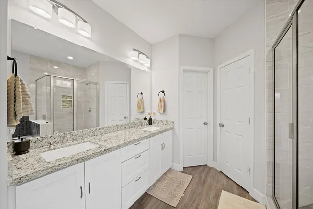 a spacious bathroom with a granite countertop double vanity sink a mirror and a