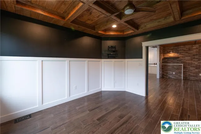 a view of an empty room with wooden floor fireplace and a window