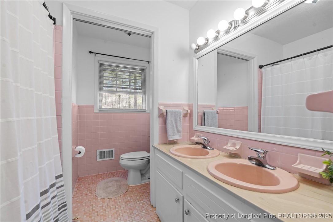 1284 Old Stage Road Fairmont, NC 28340 - Photo 30 of 48 a bathroom with a double vanity sink toilet and a mirror