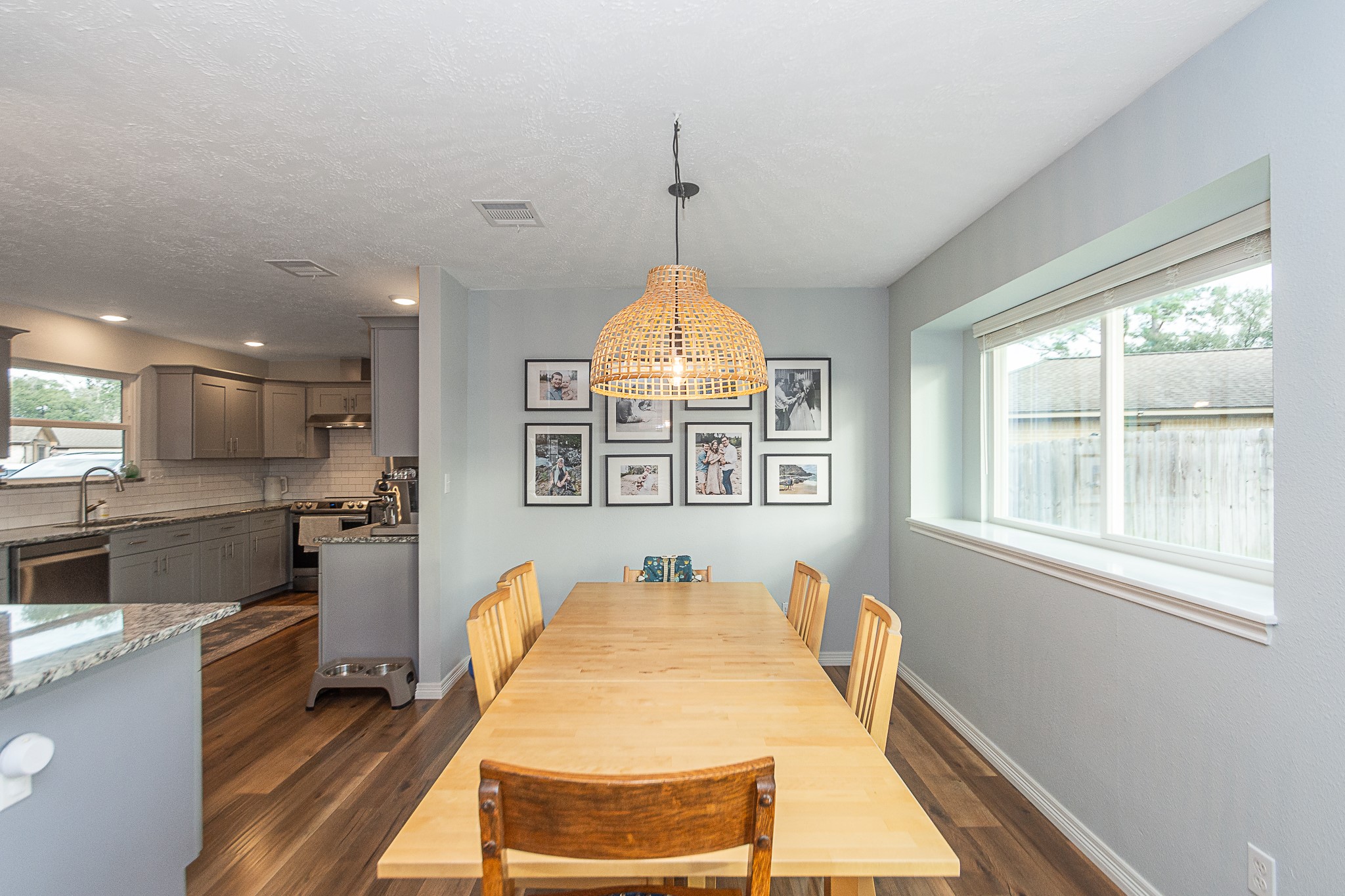 4830 Lost Oak Drive Spring, TX 77388 - Photo 12 of 41 This photo showcases a bright dining area with a wooden table and chairs, adjacent to a modern kitchen. It features a large window for natural light, hardwood floors, and a stylish pendant light.