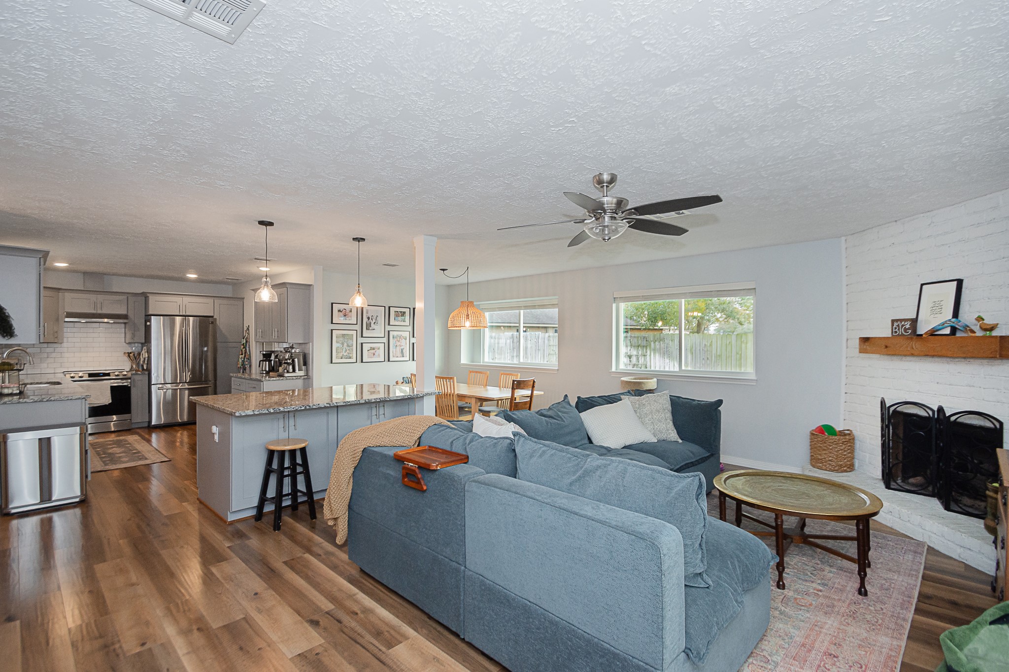 4830 Lost Oak Drive Spring, TX 77388 - Photo 15 of 41 This open-concept living area features a modern kitchen with stainless steel appliances and granite countertops, seamlessly flowing into a cozy living room with a fireplace. Large windows provide natural light, while wood flooring and neutral tones create a warm, inviting atmosphere.