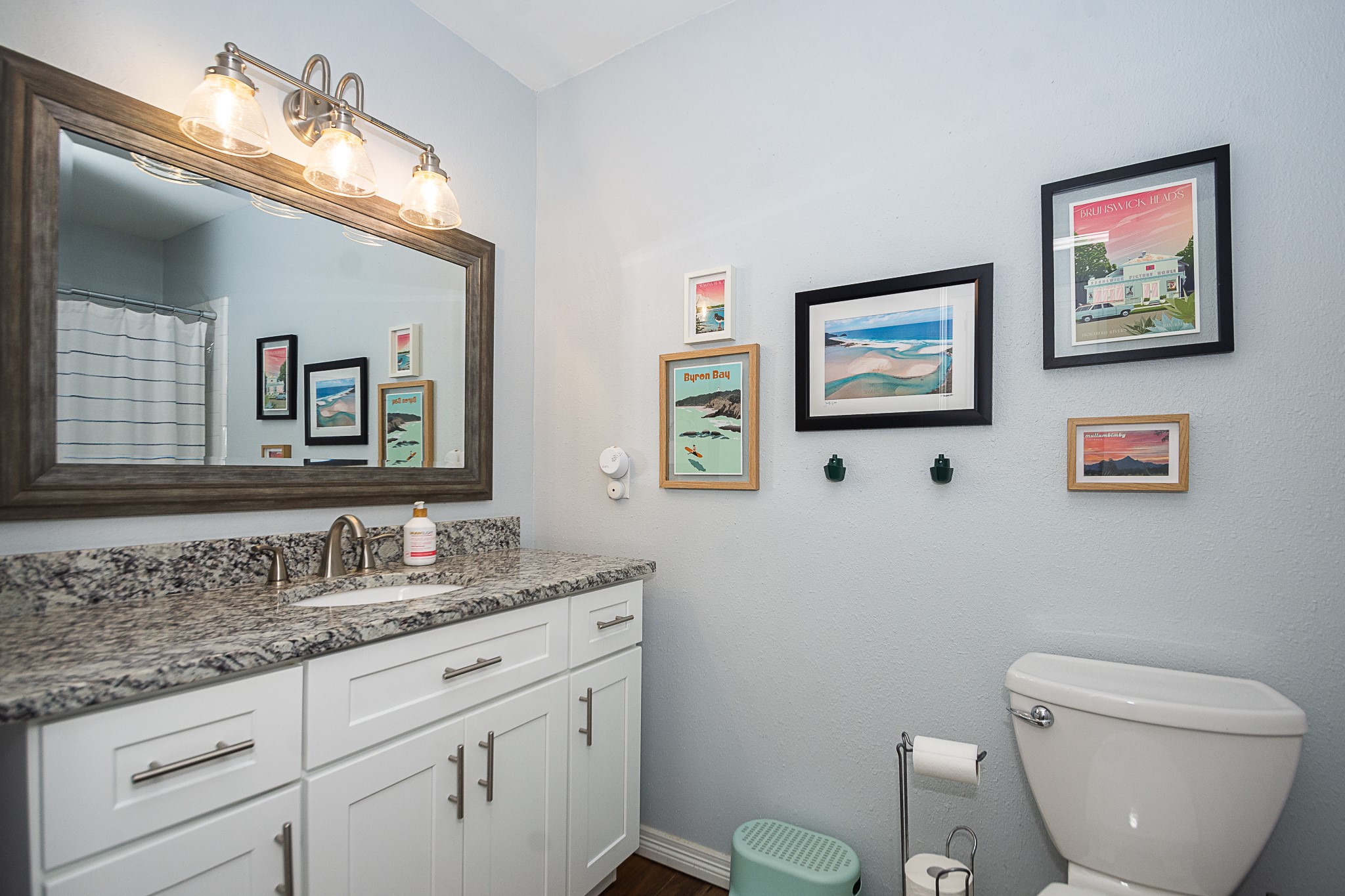 4830 Lost Oak Drive Spring, TX 77388 - Photo 24 of 41 This bathroom features a granite countertop with a sink, framed mirror, and stylish light fixtures. It includes a white vanity with ample storage, a toilet, and decorative wall art. The space is clean and modern, with a light color scheme.