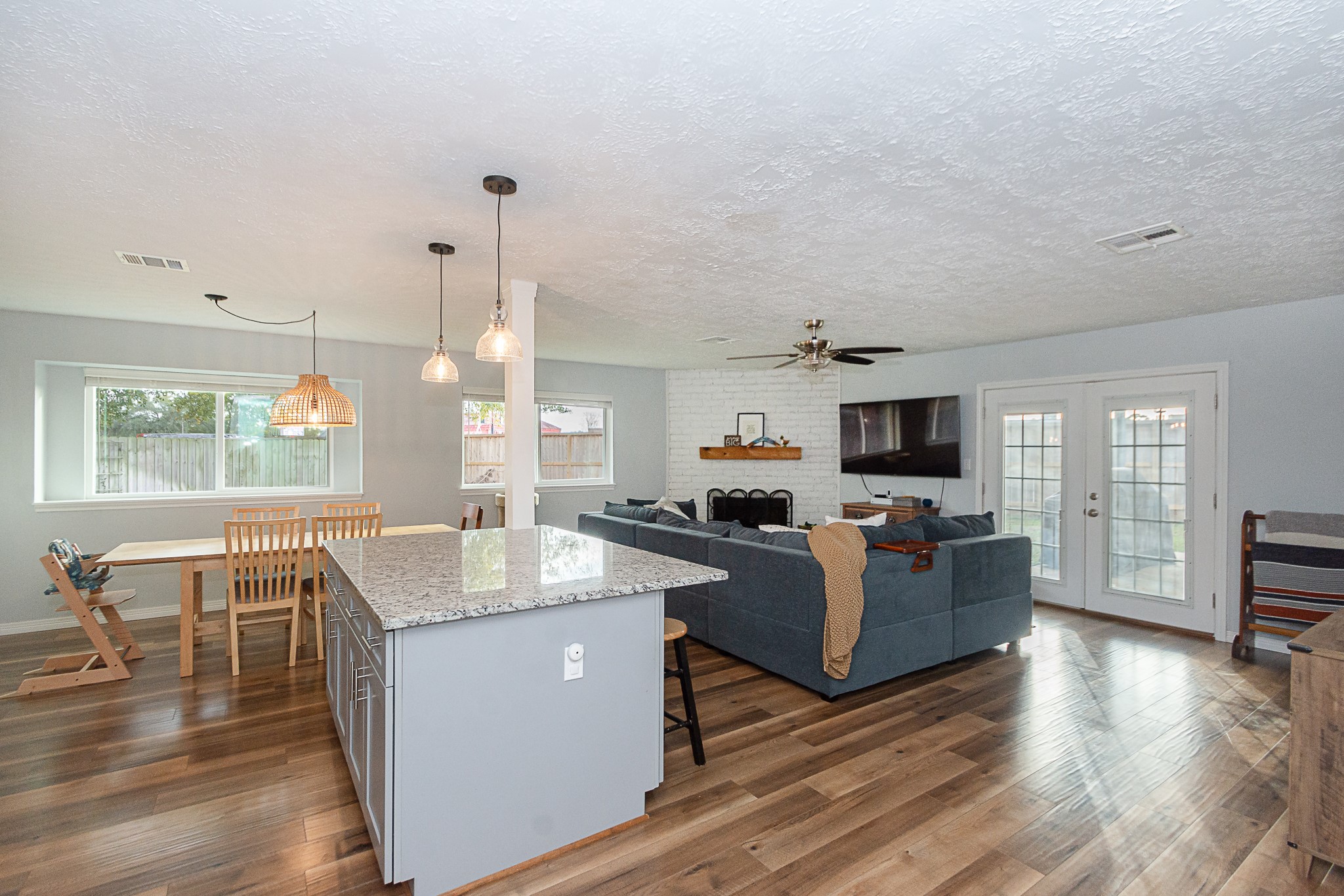 4830 Lost Oak Drive Spring, TX 77388 - Photo 10 of 41 This open-concept living area features a modern kitchen with a large granite island, cozy dining space, and a spacious living room with a fireplace and mounted TV. Natural light flows in through multiple windows and French doors, highlighting the elegant wood flooring.