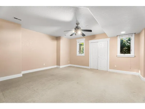 an empty room with chandelier fan and windows