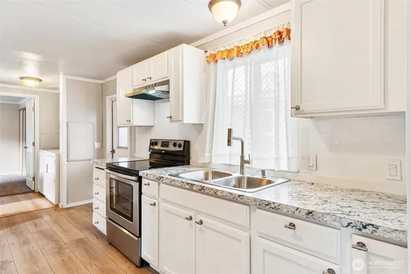 a kitchen with granite countertop a sink a stove and cabinets