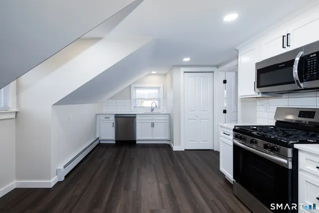 a kitchen with stainless steel appliances a white cabinet and a stove top oven