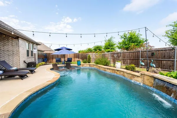 a view of a swimming pool with a patio and a yard