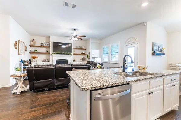 a kitchen with stainless steel appliances granite countertop a sink dishwasher and cabinets with wooden floor