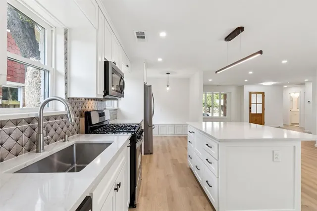a kitchen with granite countertop a sink stainless steel appliances and cabinets