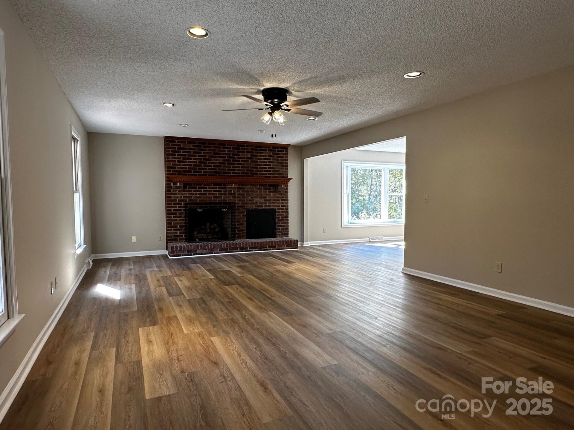 1080 Gin Road Rockwell, NC 28138 - Photo 6 of 34 an empty room with wooden floor fireplace and windows