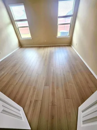 a view of an empty room and wooden floor and windows