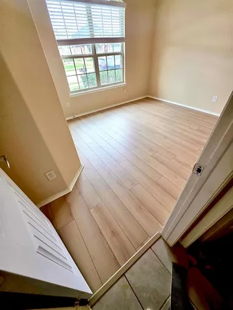 an empty room with wooden floor and windows