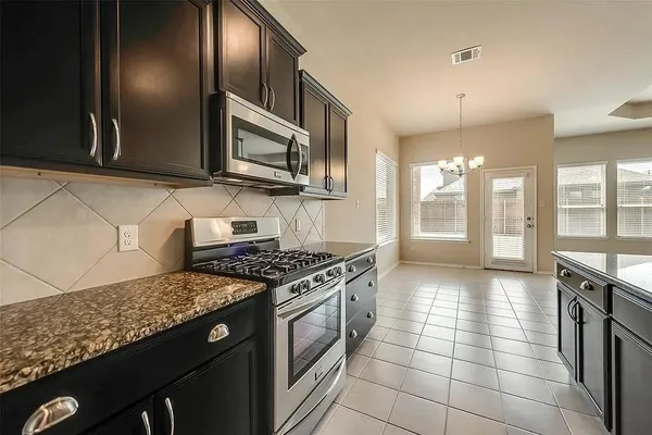 a kitchen with stainless steel appliances granite countertop a stove a sink and a microwave